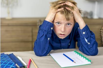 Enfant devant un cahier avec l'air abattu